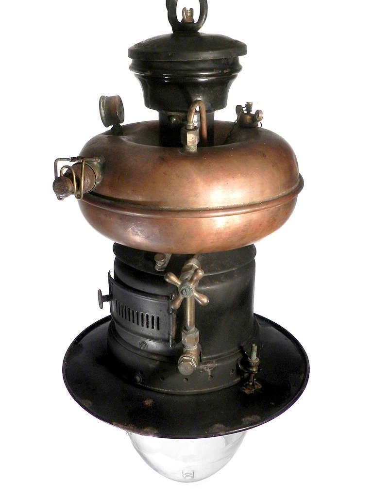 This is one of my favorite lamps and have brought them back from all over the world. This example is one of the most interesting with its many details including: copper donut tank, signed shade, 2 oval plaques, trap stove door, large brass valves