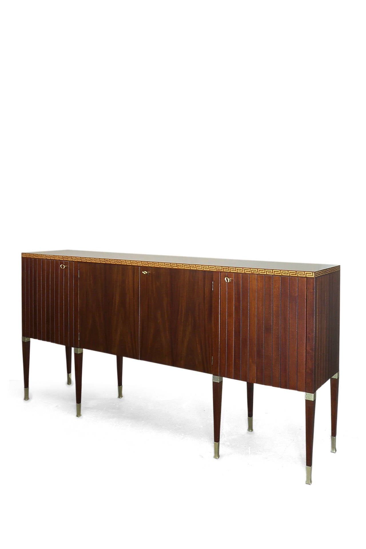 Sideboard of veneered and solid mahogany featuring a maple inlaid Greek key. The eight brass fitted legs of Neo-Liberty style. 

Literature: Roberto Aloi, L'arredamento Moderno IV serie, Milano, 1949, see plate 579 for a similar example.