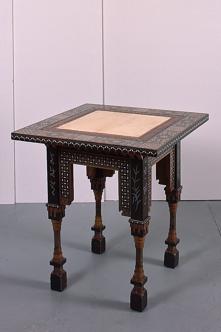 An exemplary table by Carlo Bugatti. The base featuring pewter inlay of fantasy calligraphy and metamorphic insects supporting an intarsia and brass framed goatskin top.