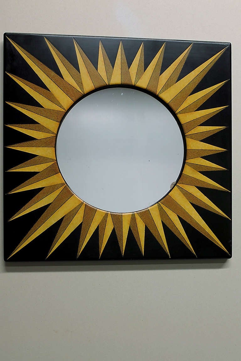 A mirror by Piero Fornasetti in a hand-painted square frame with sunburst design.