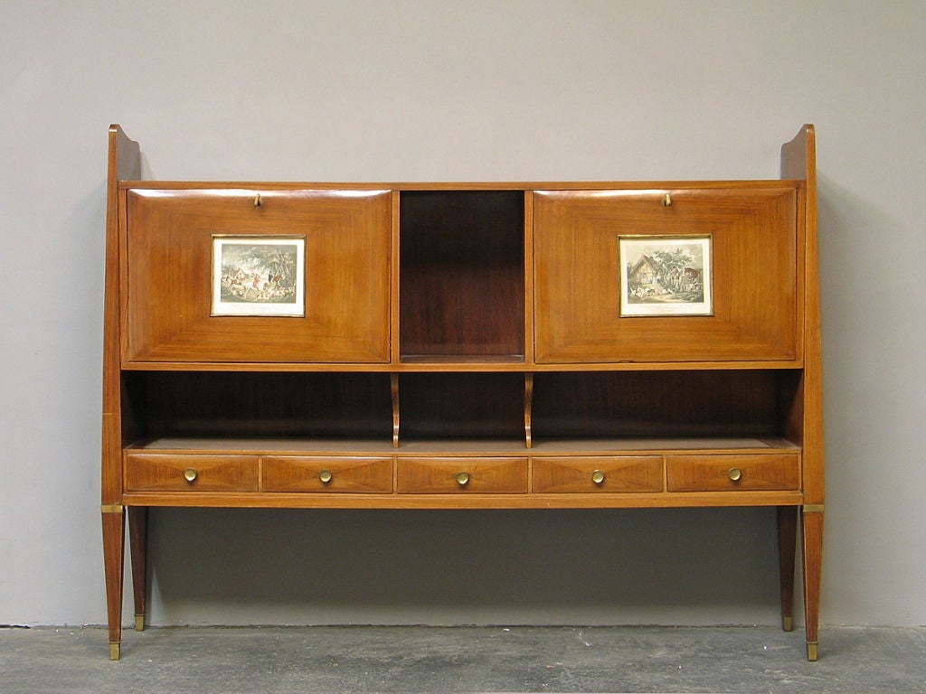 An extraordinary shaped flap front rosewood veneered sideboard by Milanese architect Paolo Buffa. The two flaps with a framed print on each center concealing a maple veneered secretary to the right and a glass and brass sheet covered bar to the