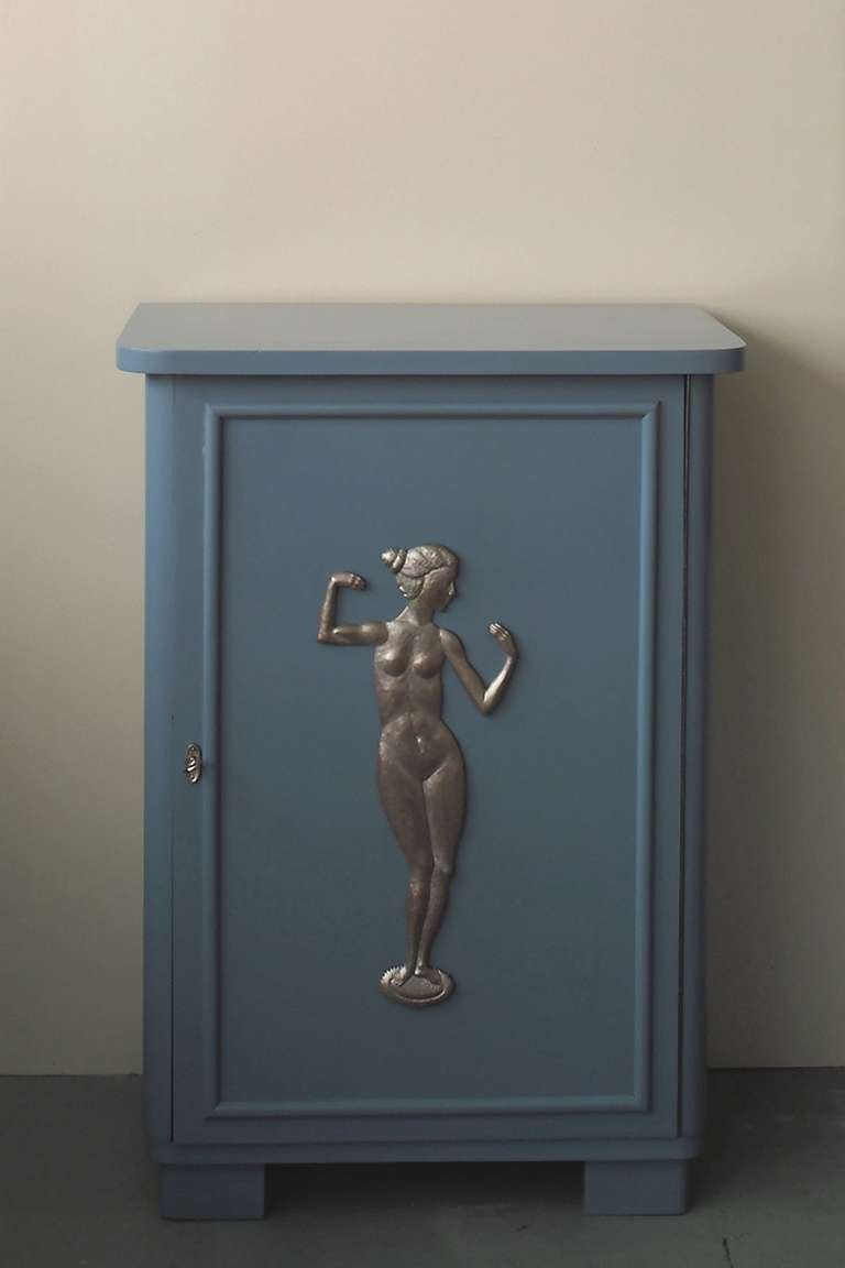 Pigeon blue lacquered cabinet showing a carved and silvered relief in the center.