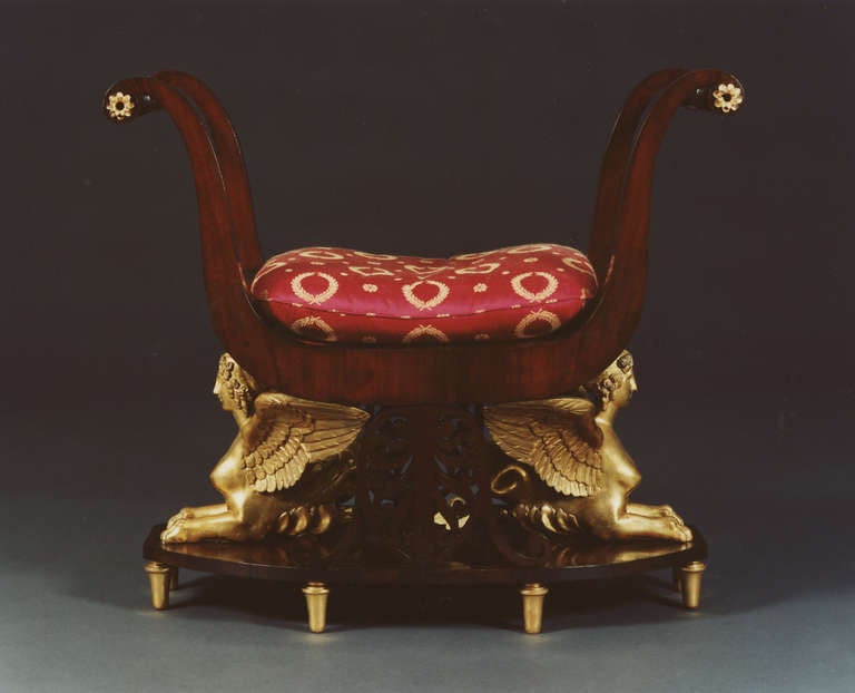 The seat flanked by the paired scrolling downswept ends joined by turned arms, the seat raised on two opposing sphinxes and two pierced inverted anthemions, the whole raised on a shaped oval plinth above eight tapering gilt feet. Detailed research