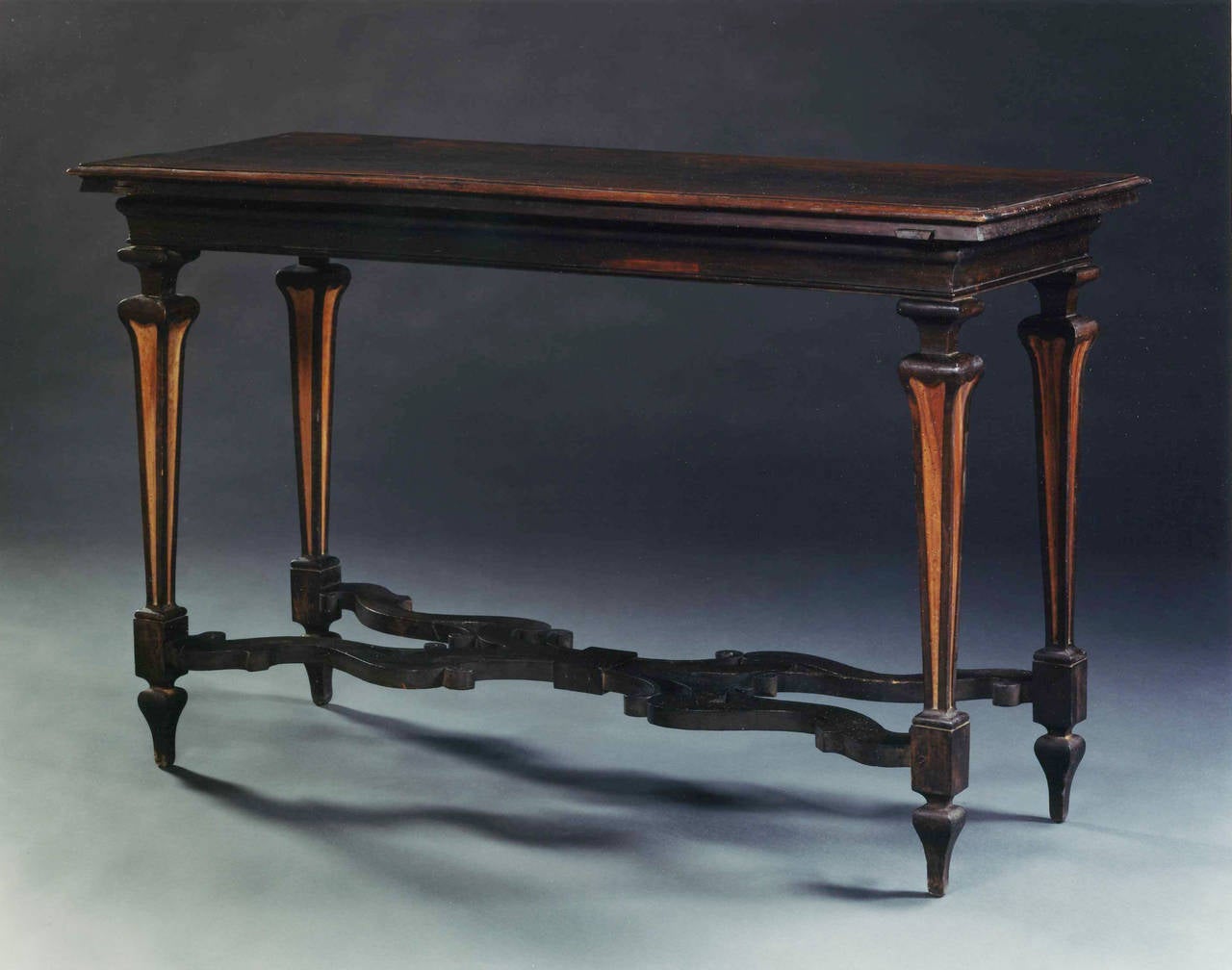 The rectangular top with moulded edge above a shaped frieze, the whole raised on four square tapering panelled baluster legs, each terminating in a square plinth raised on a tapering foot, the legs joined by a shaped x-stretcher.