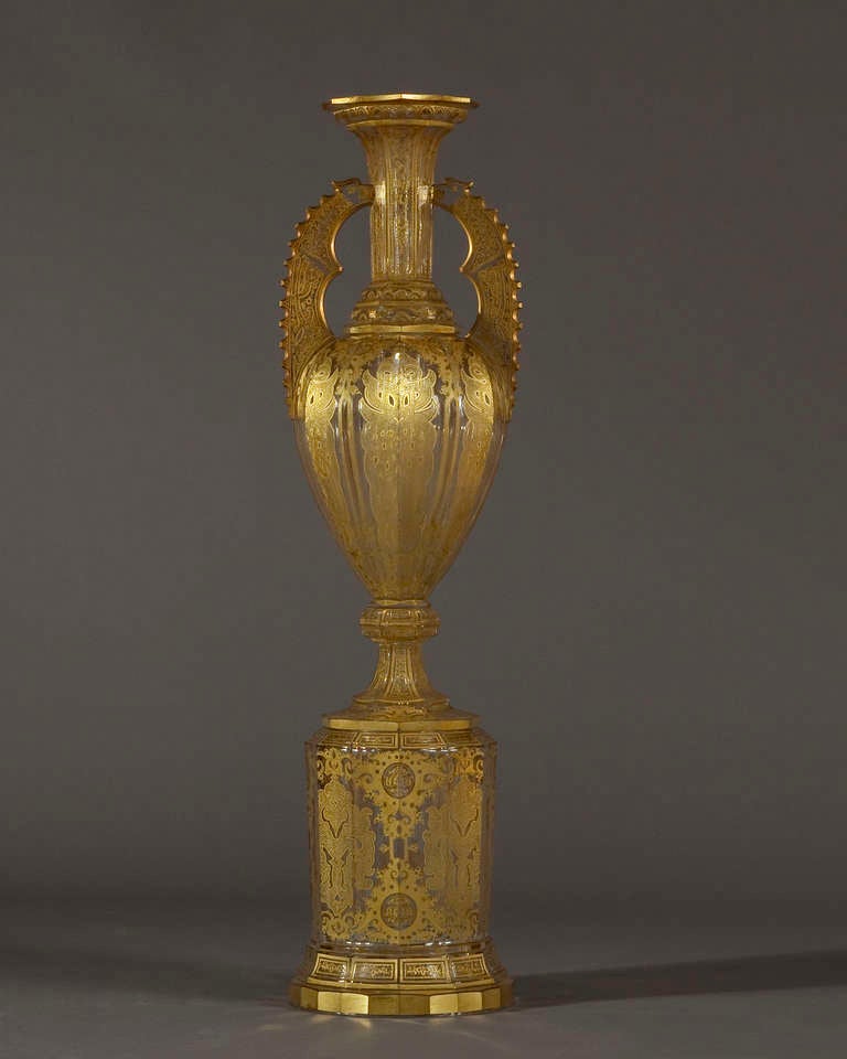 Exhibited at the 1862 London International Exhibition by Wilhelm Hoffmann, this monumental vase is of colorless glass and gilded decoration. The faceted flared neck resting upon a shaped and molded base flanked by a pair of eagle-headed double