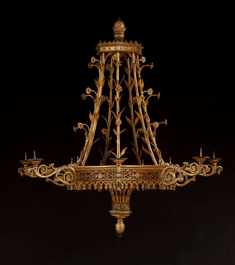 The seven sided corona set with applied stars and surmounted by an acorn finial. The seven suspension 'chains' formed as foliate stems. The carrying ring with old replaced turned knops to the edge has seven incurved pierced classical foliate panels