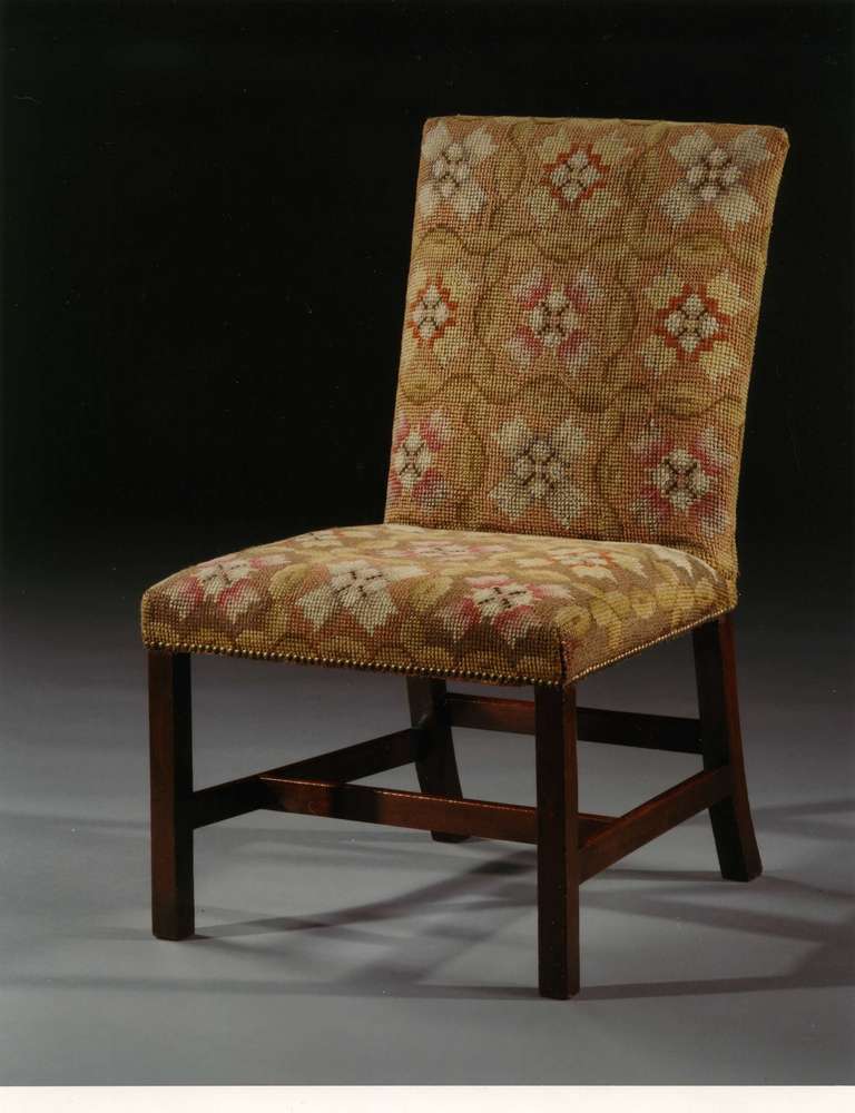 Of mahogany with original gros point wool needlework. Each with upholstered rectangular back and seat resting on square legs joined by an H-shaped stretcher. Restoration to needlework commensurate with age.