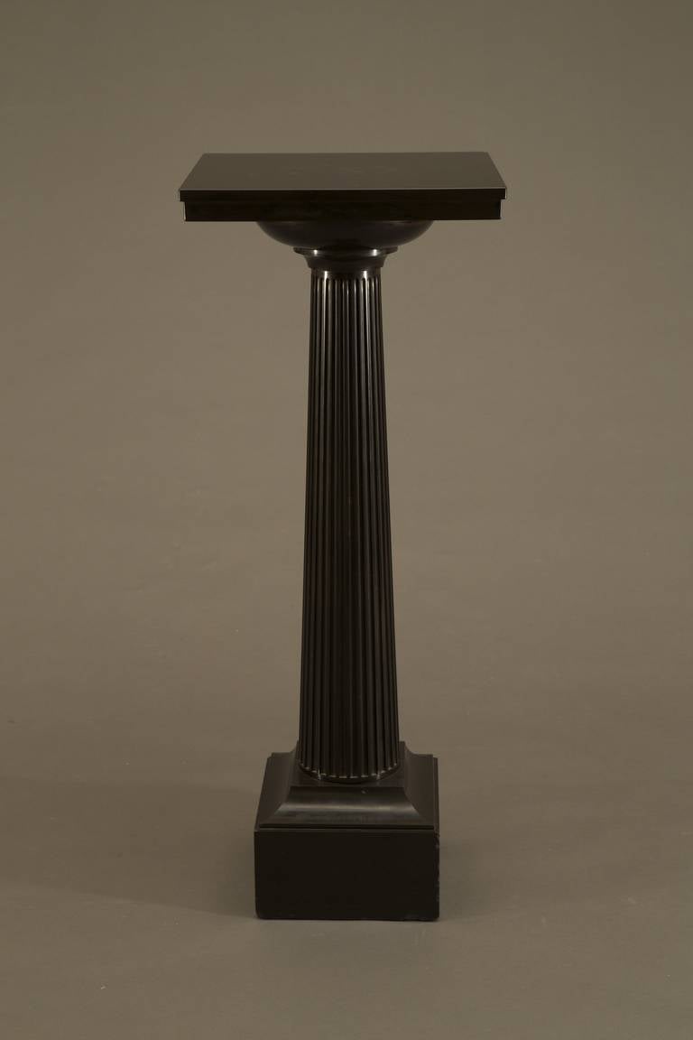 Of Ashford black marble. Each with a square plateau raised upon a tapering Doric shaft and stylized capital. The whole resting on an incurved base supported by a square block plinth. A few minor chip repairs, one plateau with old repair.