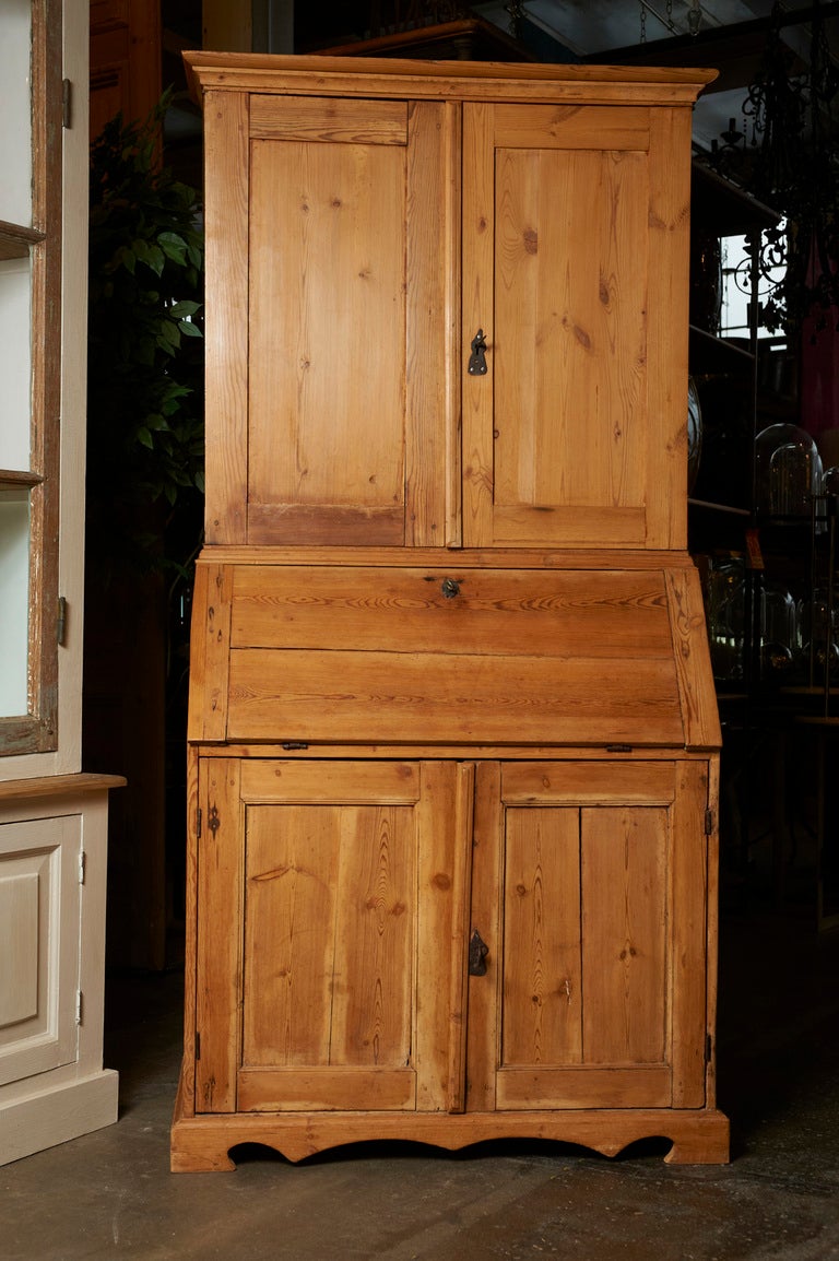 English pine secretaire/bookcase, mid-19th c., of smaller pleasing proportions with a slant front fitted interior desk, cupboards below on a wavy bracket plinth and bookcase top.