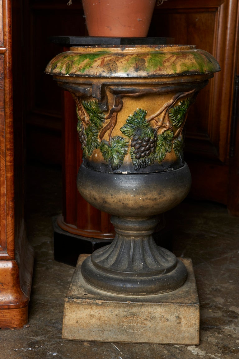 Scottish glazed terracotta garden urn on plinth with embossed fern laves and grapes, stamped 