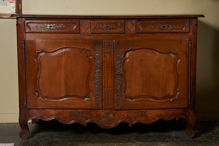 French fruitwood buffet, c. 1780-90, from the Southwest of France, with three shaped and molded front drawers divided by marquetry diamonds over two asymmetrical shaped doors, carved scalloped apron and escargot feet. Superb iron hardware!