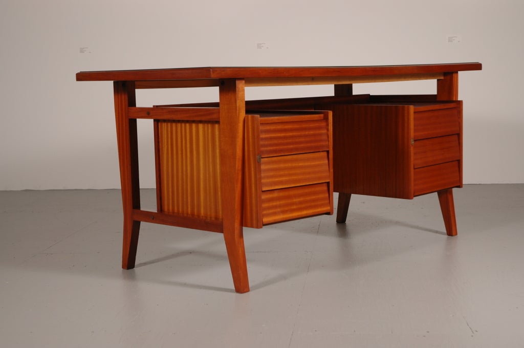 Very nice  6 drawer desk, after a design by Gio Ponti in mahogany with mauve colored back painted glass top.
Interior of the drawers are pvc. Manufactures mark impressed  