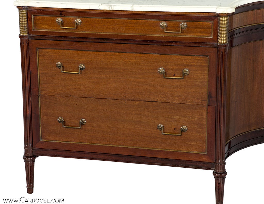 Louis XVI style mahogany marble top commode with a classic design featuring serpentine concave sides, turned columns and brass appointments. Original rich mahogany patina finish.