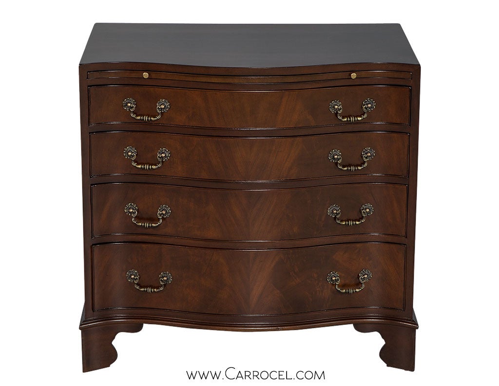 A pair of serpentine fronted, flamed mahogany chest of drawers. Refinished in 2014 to a rich mahogany brown. Graduated four-drawers with a dressing slide. Features original brass pulls and bracketed feet.