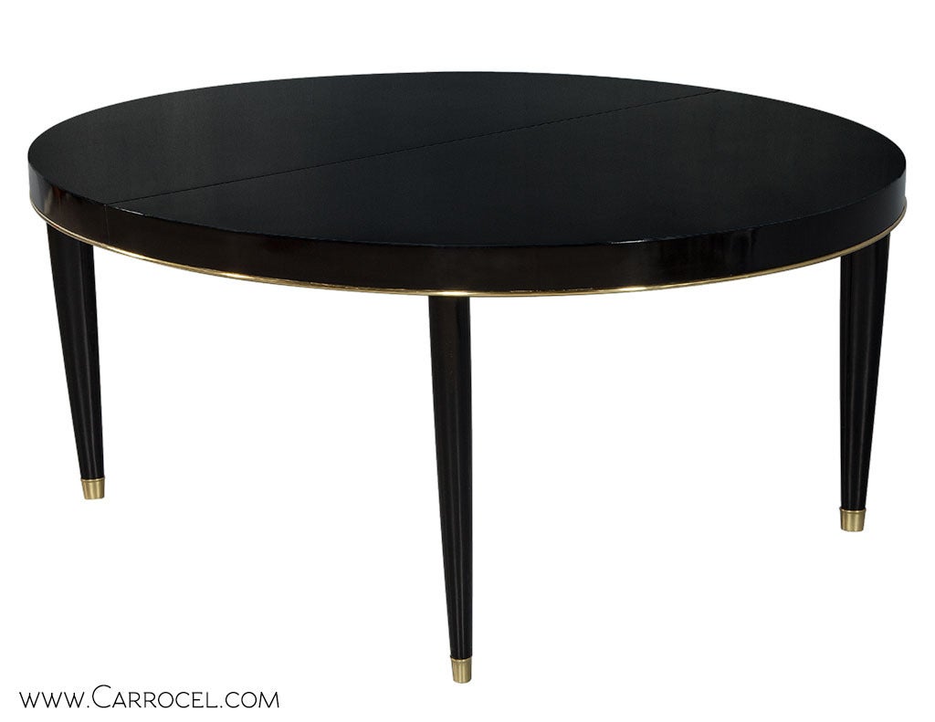 Beautiful oval gateau top dining table. Accented with brass trim, elegant tapered legs and finished in polished black lacquer. Extends to 96” with leaf (24