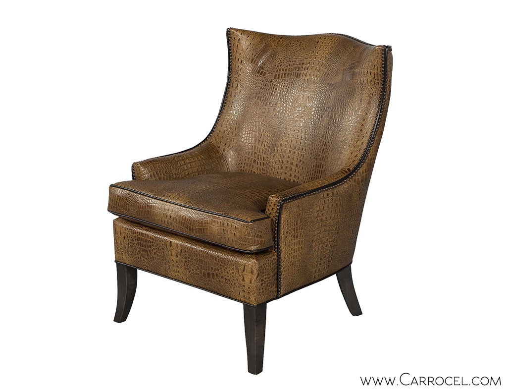 This modern wing chair features a sophisticated twist on a traditional look. Upholstered with embossed croc motif leather, the shape is defined by black leather piping and a double nail head trim. Customize this frame by selecting your finish and