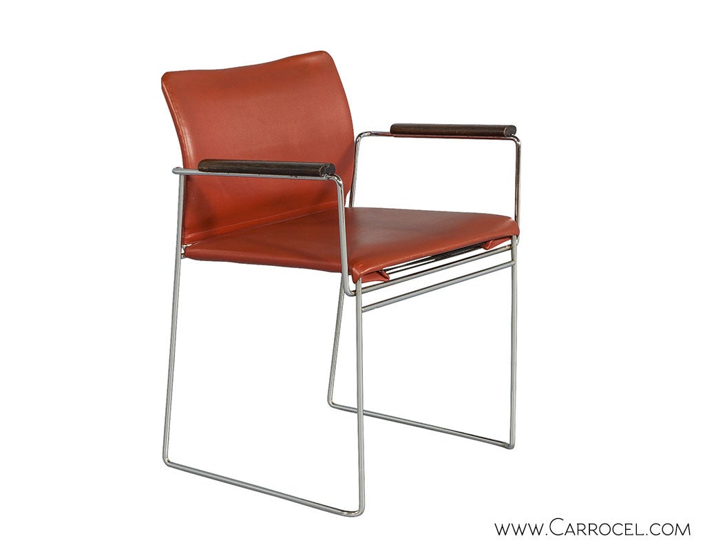 Vintage chrome arm chair with a tubular frame wrapped in a deep orange vinyl and walnut wood arm rests.