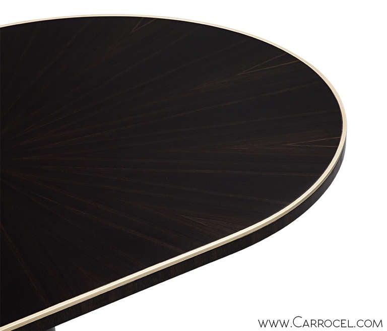 Custom-made by Carrocel Oval Modern Deco styled Macassar dining table. Accented with a brass trim top edge inlay, pedestal band and base feet. Hand polished to a mirror high gloss finish.