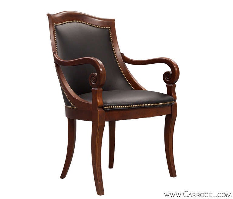 These arm chairs are a fine example of neoclassic style with a stylish gentleman's flair perfect for a library, home office or study. The chairs were upholstered in black leather and appointed with brass head to head hand applied furniture tack by