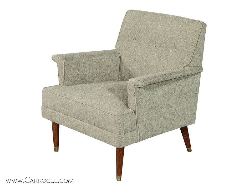Pair of Vintage Mid Century arm chairs, featuring a lightly tufted seat back, newly upholstered in a dove grey fabric with a slightly tapered brass capped teak leg.