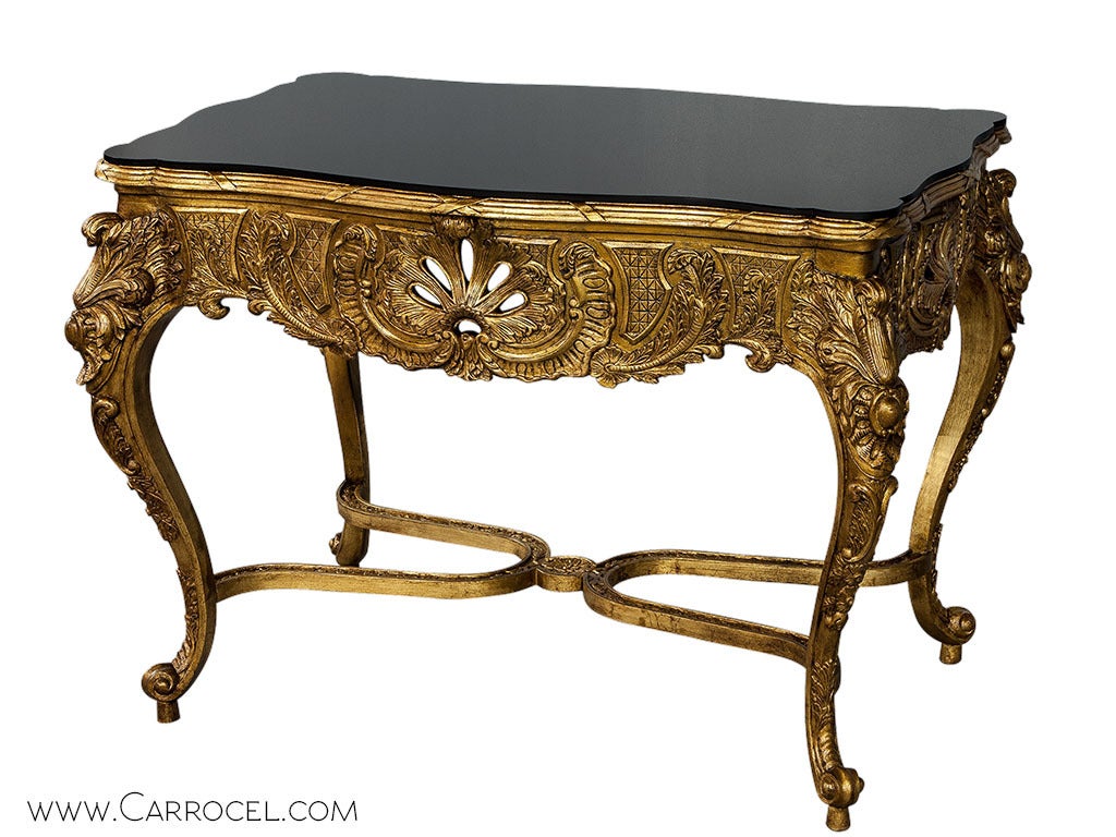 Modelled on boldly antique lines, this console table promises to bring a touch of regal splendour to the setting it is placed in. A rich gold leaf frame, intricately carved in the typical Louis XV fashion, is complemented by a sleek black glass