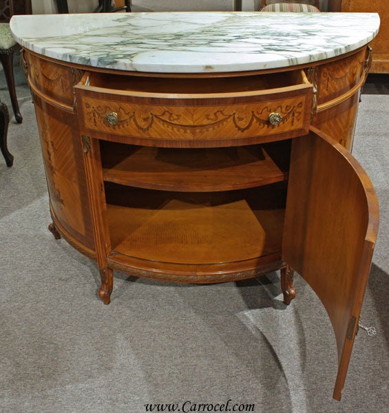 Here we have a stunning satinwood & tulip wood commode in pristine condition.  Made in the 1940s, this marble top demi-lune is styled after the much-sought after Louis XV era of furniture design and features solid brass hardware, hand-painted floral