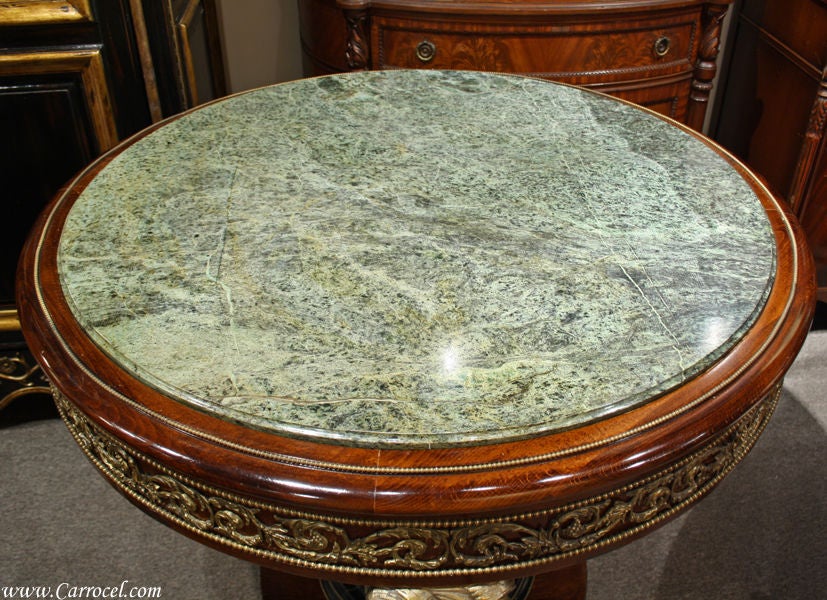 This is truly a one-of-a-kind piece of art.  It is made from gorgeously figured mahogany with hand-carved solid brass accents generously adorning each face of the table.  With its original slab of marble intact and an ebonized pedestal base that