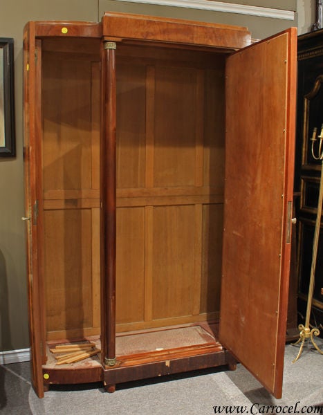 This simply gorgeous armoire was made in France in the 1930s.  It features beautifully figured Cuban flamed mahogany veneers with satinwood banding and neoclassic columns flanking the original mirrored main door.  There are 3 doors in total and