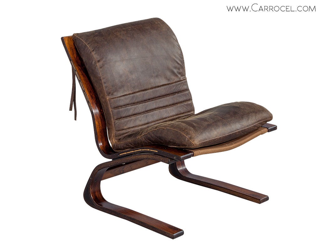 Combine a vintage cantilevered rosewood frame with a chic stroke of distressed leather upholstery, and you're left with no choice but to make a style statement! This lounge chair with an authentic mid century frame restored with new leather