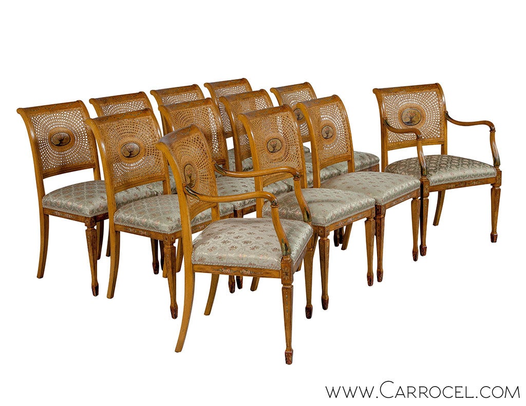 A set of 14 Corneilo Cappelini hand painted dining chairs in the style of Robert Adam. The set includes a mix of armchairs and side chairs made of fruitwood frames with cane backs, upholstered seats and square tapered legs ending in spade feet; the