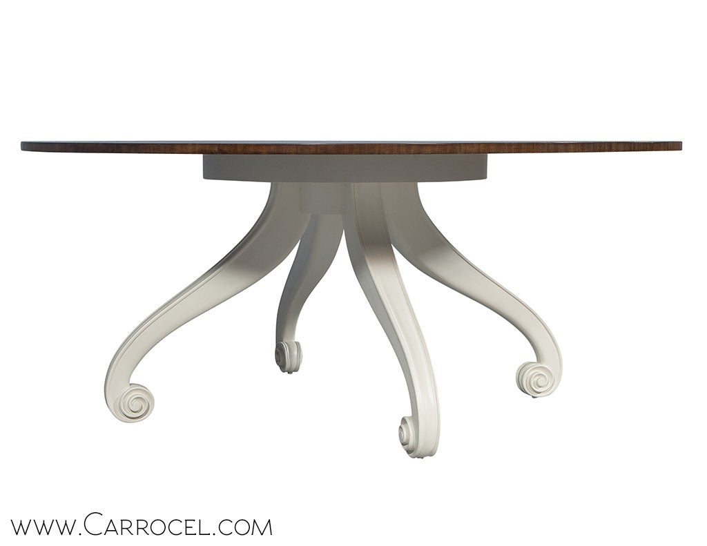 A tribute to classical proportions and contemporary minimalism, this grandiose dining table has a slim circular top with a feathered mahogany starburst finish, projecting over a four footed pedestal constructed as a reinterpretation of the Flemish
