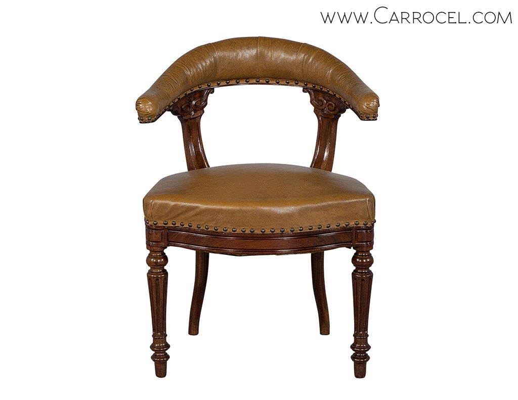 An antique Louis XVI mahogany fauteuil in excellent condition, from the Carrocel Original collection, with an arched backrest and serpentine seat front, both upholstered in tan leather and edged with nails. The item sits on tapered fluted legs with