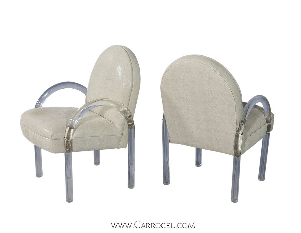 Luxurious Hollywood regency style lucite chairs designed in the manner of Charles Hollis Jones. Constructed with tubular lucite pieces arched along each side forming the legs and arms. The new upholstery is a gorgeous light shimmering suede,