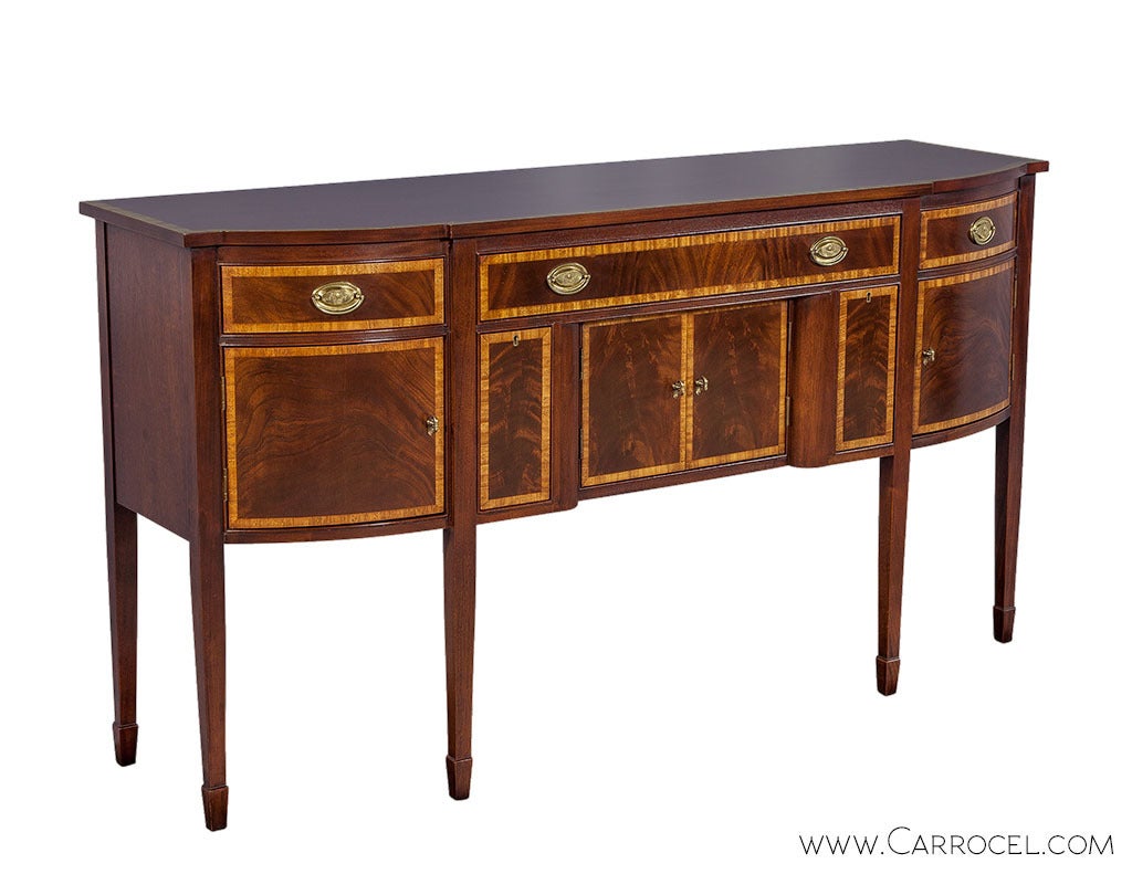 This elegant sideboard created by Ethan Allen Inc. has been designed for traditional dining rooms with a craving for elegance. The body, with subtly curved front and straight sides sit on six square tapered legs with spade feet. Flamed mahogany