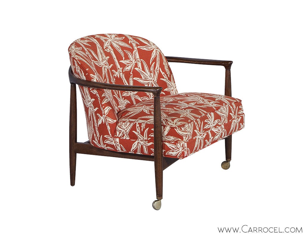 A pair of elegant authentic Selig chairs, with the characteristic Danish Mid Century features of slender wooden frames and plush cushioning. The seats and backs have original upholstery in a vivid print, while the gently curved arms and legs that