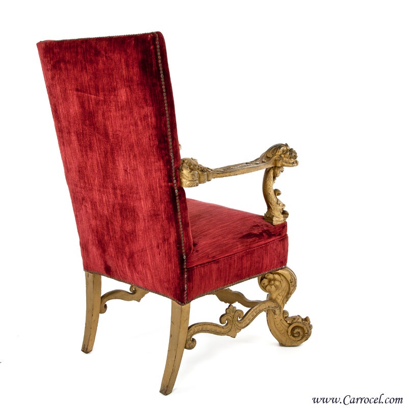 Here we have a beautiful ornately carved throne chair.  Made in America in the early to mid 20th century, this piece features stunning detailed carvings, original upholstery, and head to head upholstery nails that have acquired a lovely aged patina.