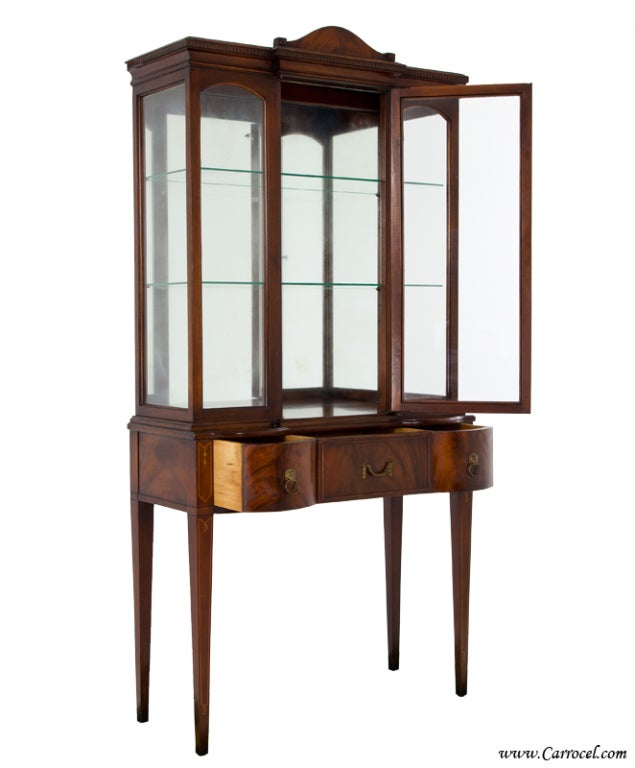 Here we have an antique early 20th century Federal style curio china cabinet.  Featuring beautifully figured crotch mahogany coupled with satinwood inlay, it draws its timeless styling from the English Hepplewhite that the Americans retooled