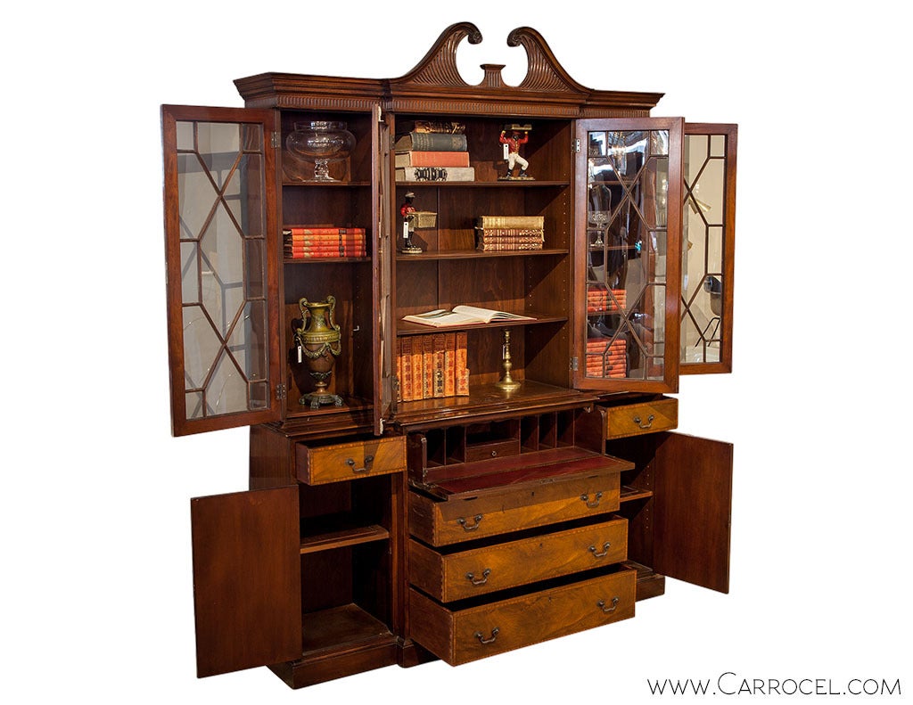 Characteristically Sheraton, this three bay mahogany breakfront china cabinet stylishly combines the boldness of rectilinear geometry with the flourish of a broken scroll pediment. All three bays have interior shelving concealed by 13 angular pane