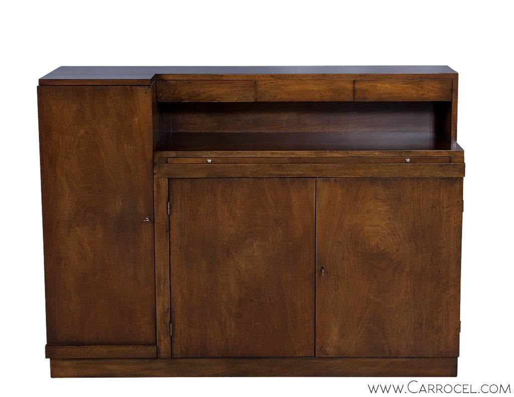 A compact, asymmetric wooden buffet with the solid proportions of the Art Deco style, consisting of various storage options, from a full height compartment on one side, to shallow drawers over another shelved compartment, to a handy surface on top.