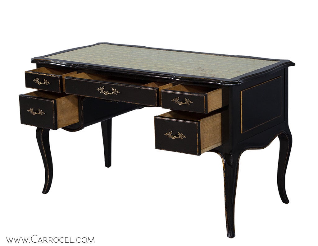 A rich set of materials adorns this vintage Louis XV Writing desk. A wooden body with a dark ebonized exterior is fashioned with a central drawer and two each on either side, cabriole legs, and a shell encrusted inlay on the top surface. The piece