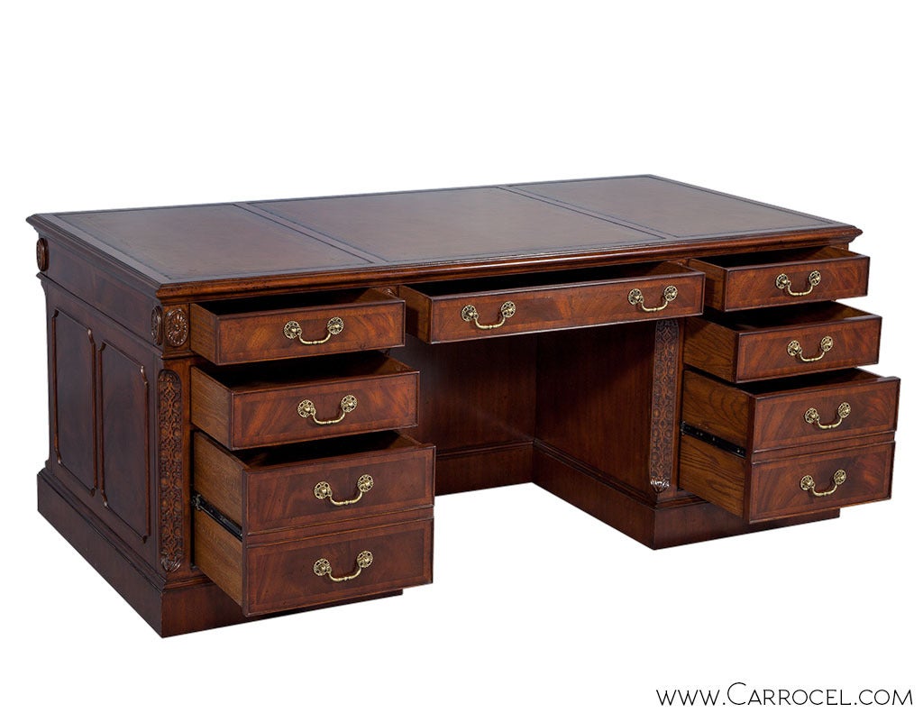 Gold tooled English leather embossed flamed mahogany executive’s desk. Fine detailed fretwork, carved inlays, solid oak dove tailed drawers adorn this finely crafted and newly made masterpiece. Finished in a rich hand rubbed and antique glazed