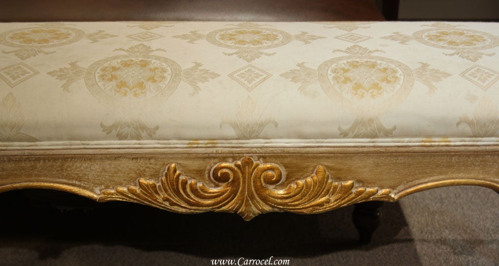 This is a French Provincial style bench done in a antiqued gold and cream brushed finish. It has gold hand-painted highlights on the carvings and the upholstery has a designer Damask fabric. It is approximately 30 years old and made in the US. View