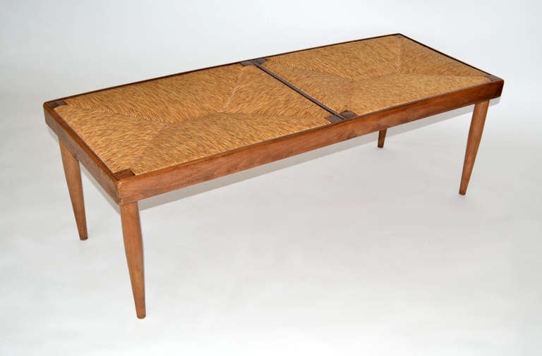 Fine studio crafted bench of walnut and woven grass. Natural wood structured frame on turned legs with two inset woven grass cord seats. Burnished stamp 