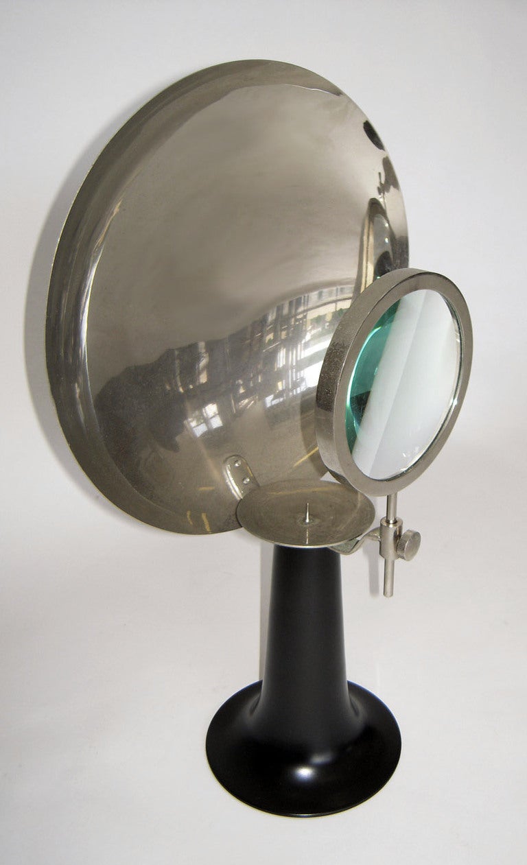 This is a very interesting and rare item that was mainly used to magnify specimens. Flared black metal candle base supporting nickel-plated parabolic reflective disk holding an adjustable magnifying glass. Could be electrified.
--Complimentary
