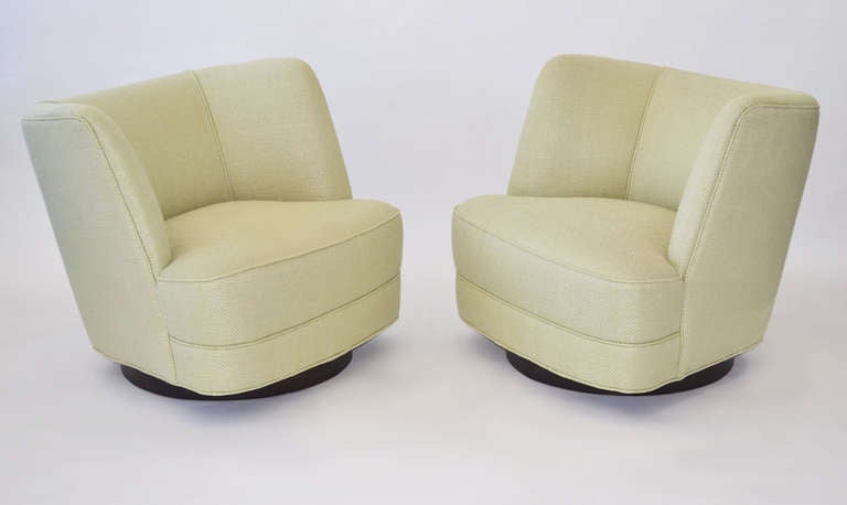 Fantastic pair of swivel lounge chairs in a barrell design on a dark finish swivel wood bases. These are very sturdy with superior swivel mechanisms. They were re-upholstered in 2006 in a Herringbone LuLu DK Fabric, and remain in great condition.
