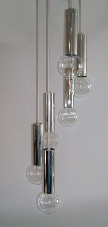 Six bulb cascading Mid-Century chrome pendant chandelier, 1960s. Six chrome column pendants, suspended from a circular white ceiling disc in a cascading spiral pattern with a 52