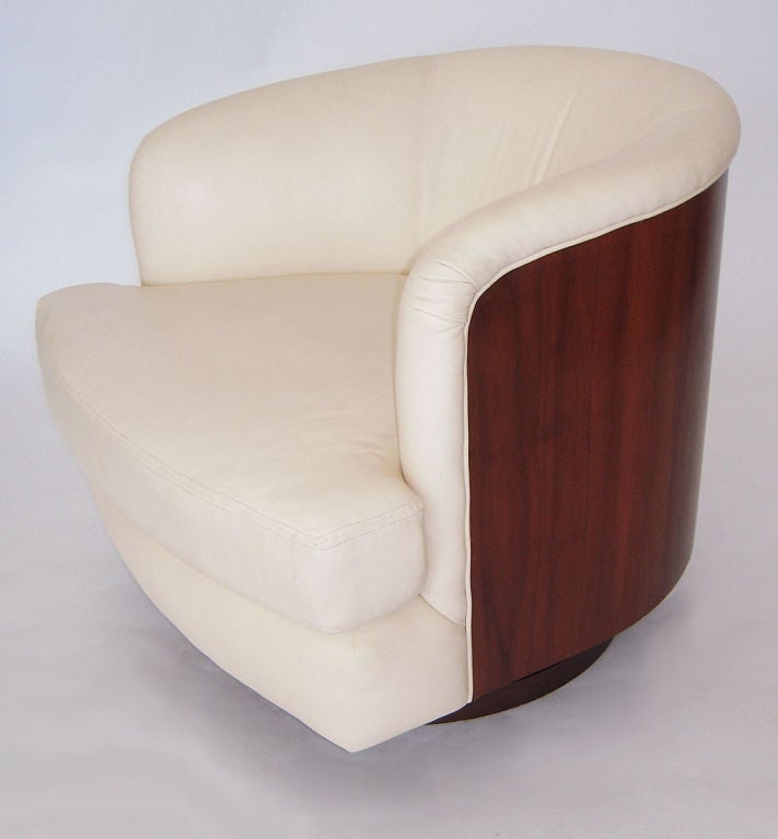 An exceptional swivel lounge chair designed by Milo Baughman. The chair bears a rosewood veneer outer shell, with very soft and supple leather type ivory upholstery. Chair rotates on a raised disc.