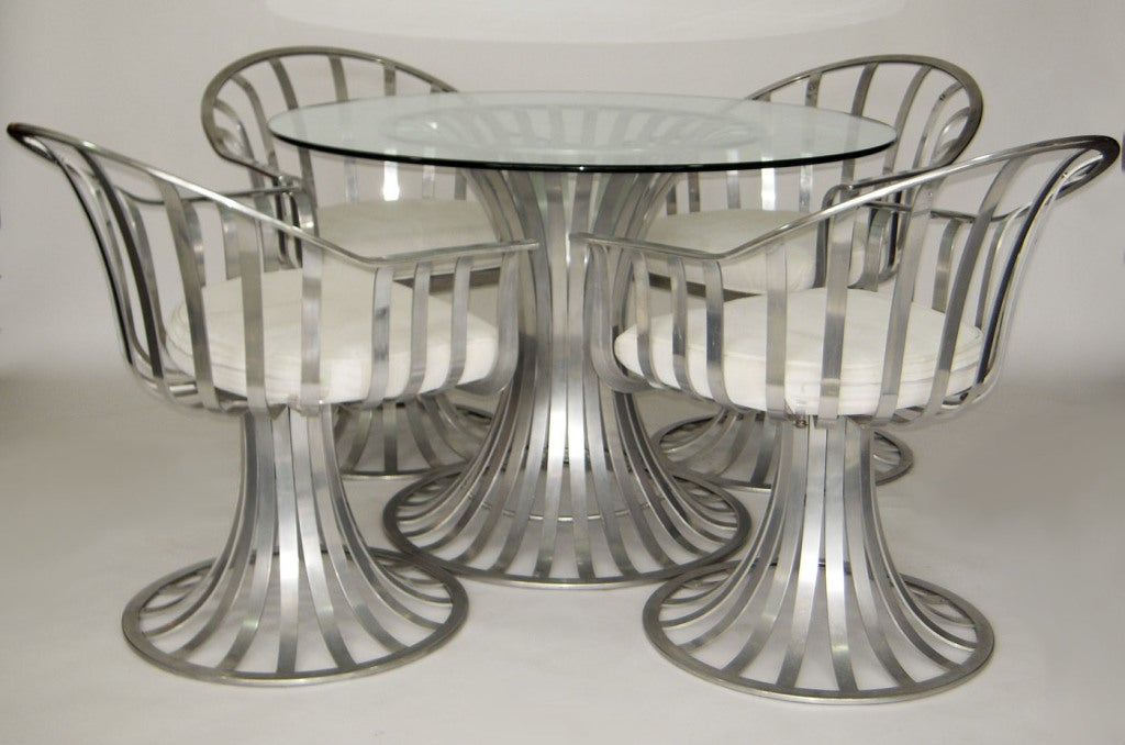 Aluminum tulip-style dining base with glass top and four matching arm chairs. Seat and back cushions are an outdoor vinyl upholstery, and the back cushions neatly attach to the built in snaps on the chairs.