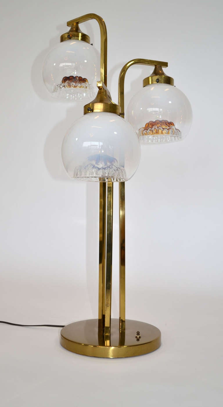 Three-arm waterfall-style Murano table lamp with three handblown glass globes with milky to clear glass and inverted sculpted amber centres, each suspended on a brass structure. A marvellous representation of all the colors when lit. By A. V.