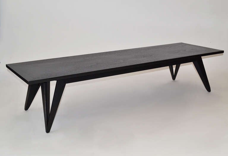 Well-executed, sleek wood coffee table in minimalist design with long rectangular top on geometric angled legs in ebony finish. Likely walnut. Stamped with serial number. In the style of pieces designed by Ponti, Ico Parisi, Bertha Schaefer and Van